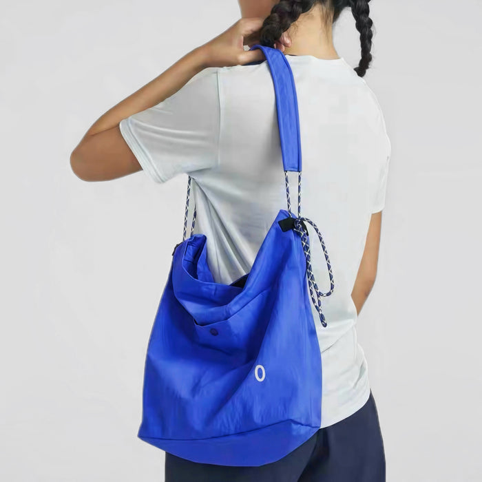 A model wearing the blue Breezy Trail Bag, showcasing the adjustable crossbody strap by knotting.