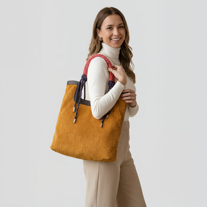 A model carrying the versatile tote bag as a shoulder bag, showcasing its pure lines and artisan braided handles.