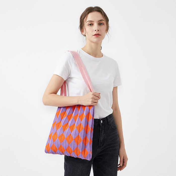 Model styling a purple and orange argyle pleated knit bag for a vibrant look.