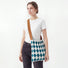 Model styling a Viridian-White argyle pleated knit bag for a chic style.