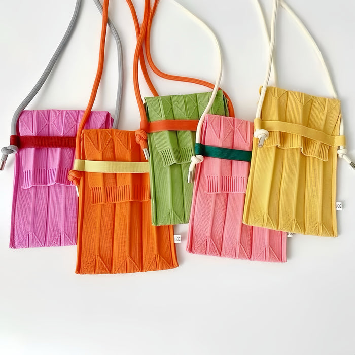 Five vivid knit polyester mini bags in pink, orange, green, and yellow with adjustable crossbody straps and flap closures.