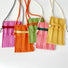 Five vivid knit polyester mini bags in pink, orange, green, and yellow with adjustable crossbody straps and flap closures.