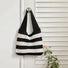 A black and white Wide Stripe Crochet Bag hanging on a door, easy for commuting and weekends.