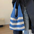 Model carrying a  Wide Stripe Crochet Bag in blue handheld, great for everyday carry and travel.