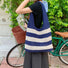 Model carrying a navy blue striped bag on shoulder , ideal for city walks and gifting.