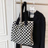 Black and white checkered knit tote hanging on a rack, perfect for a minimalist wardrobe.