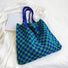 Close-up of the blue and green checkered woven bag on a white fabric background.