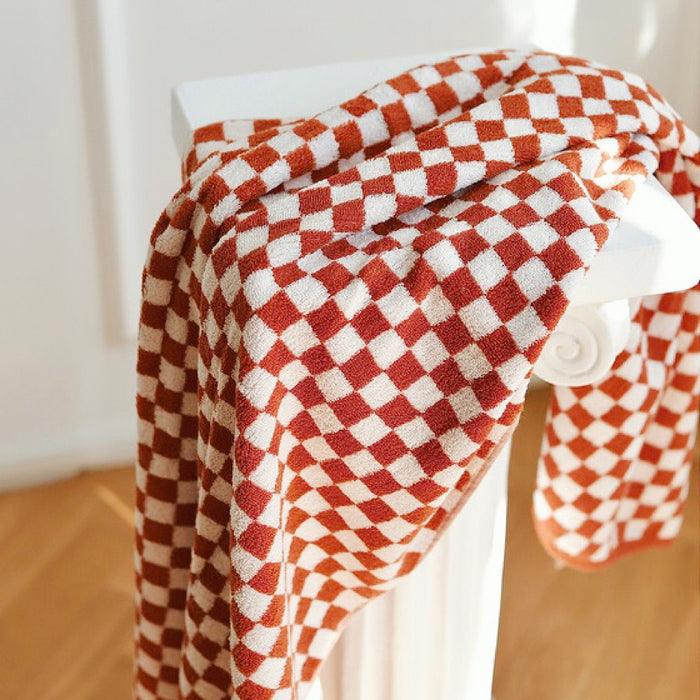 Red and white checkerboard cotton bath towel draped over a white stand.