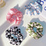 Four satin checkerboard scrunchies in pink, blue, black, and green.