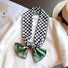 Model wearing a plaid satin scarf in green, easy for weekend styling and gifting.