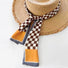 Model wearing a plaid satin scarf in orange, great for office layering and commuting.