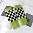 Lime green checkered knit gloves on book; soft texture ideal for cozy reading or student study sessions.