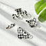 Four black and white checkered acrylic hair claws in various shapes.