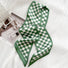 Angled view of Green and white checkered silk-like skinny scarf on a white surface.