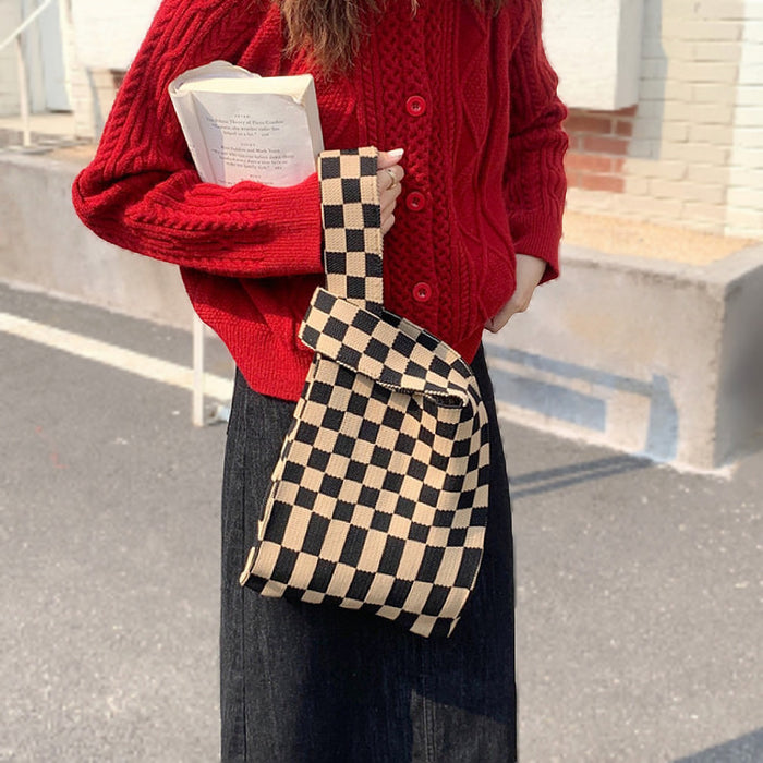 Model carrying the black and coffee checkered tote bag as a versatile carryall.