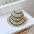 Front view of green striped foldable straw hat. Playful summer aesthetic for outdoor leisure activities.