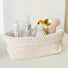Front view of beige crochet storage basket with cosmetics and makeup brushes inside, ideal for tidy shelves and daily use.