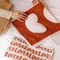 Hands holding a red and white cotton face towel with a large heart design.