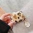 Model Hands holding a leopard print airpods case with shell charm, ideal for gifting and everyday carry.