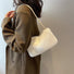 Model carrying a white mini fluffy shearling baguette bag on the shoulder, ideal for city walks and gifting.