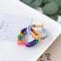 Two braided rainbow elastic hair rings on a white tray.