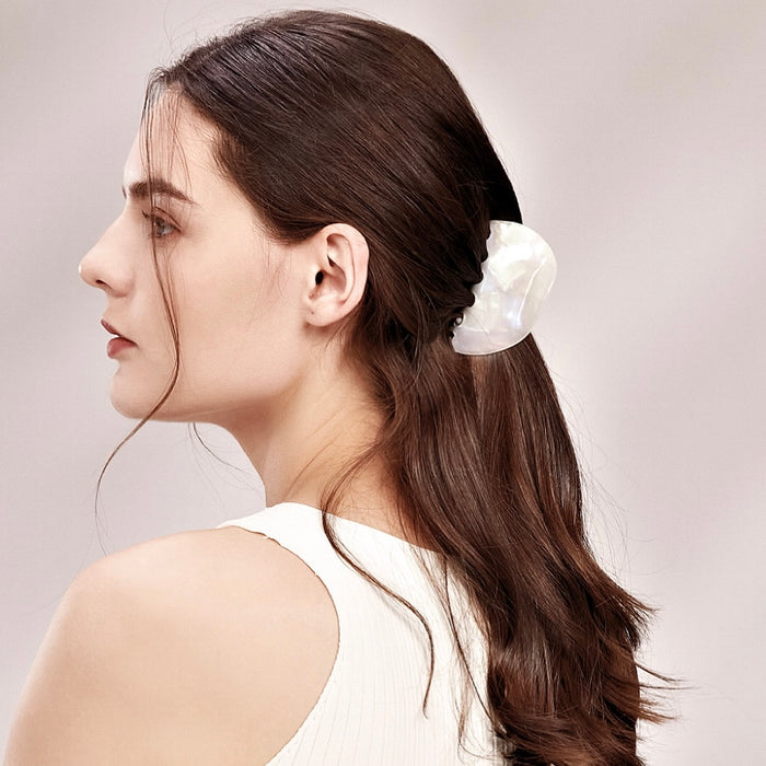 Model wearing a Shell hair claw in white luster, ideal for everyday outfits and office looks.
