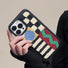Model holding the sherpa fleece phone case, showcasing the artistic geometric embroidered design.