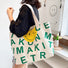 Model carrying a green smileface canvas tote bag on the shoulder, easy for commuting and weekends.