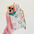 Model holding Smile Case With Charm. Minimalist smile graphic paired with a decorative charm.