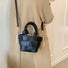 Model carrying a black Woven Leather Mini Basket Bag as crossbody, ideal for errands and gifting.