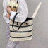 Model carring a Woven Straw Tote Bag with Black Stripe, great for everyday carry and travel.